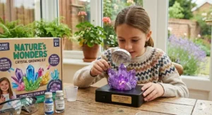 A young girl using a magnifying glass to inspect the geometric facets of a home-grown hedgehog crystal.