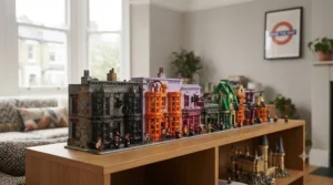 The large-scale LEGO Harry Potter Hogwarts Express Collectors' Edition (76405) train set is shown built and displayed on a bespoke wooden cabinet. The locomotive and carriages, including the 'Platform 9 ¾' sign and carriage interior details, are sharply in focus. The background shows a typical London terraced house view through a window, emphasising the set as a premium display piece for UK fans.
