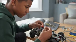 A teenager focused on assembling a detailed LEGO Technic vehicle, demonstrating the engaging nature of the construction system.