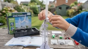 Close-up of a child carefully attaching rotor blades during the assembly of an educational wind power kit for kids.